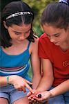 Two Girls Looking at Snail Outdoors