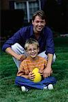 Portrait of Father and Son Sitting Outdoors with Football