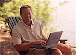 Portrait of Man Sitting in Chair With Laptop Computer near Lake
