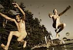 Couple en maillot de bain, sauter dans l'eau de lacs Belgrade Dock, Maine, États-Unis