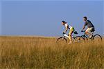 Couple, faire du vélo à travers champ de hautes herbes, lacs de Belgrade, Maine USA