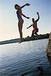 Couple in Swimwear, Jumping into Water from Rocks Belgrade Lakes, Maine, USA