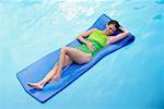 Woman in Swimwear, Lying on Air Mattress in Swimming Pool