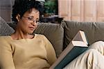Woman Sitting on Sofa, Reading Book