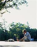 Man Sitting on Dock, Drinking From Mug with Dog Bala, Ontario, Canada