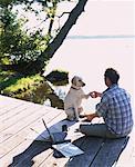 Mann sitzt auf Dock mit Hund schütteln Pfote, Bala, ON, Kanada