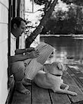Homme assis dans l'embrasure de la porte, lire le journal avec chien Bala, Ontario, Canada