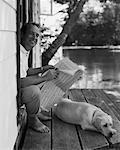 Mann sitzt in der Tür, lesen Zeitung mit Hund Bala, Ontario, Kanada