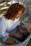 Femme assise dans le hamac, ordinateur portable à l'aide