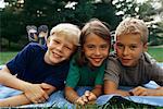 Portrait of Girl and Two Boys Lying in Field, Toronto, ON Canada