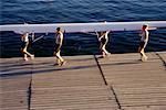 Female Rowers Carrying Boat on Dock