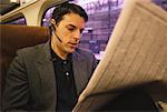 Businessman on Train, Using Telephone Headset, Reading Newspaper