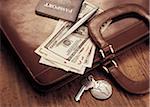 International Currency, Passport And Pen on Briefcase with Keys