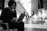 Femme d'affaires à l'aide d'ordinateur portable et un téléphone cellulaire dans le Terminal