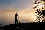 Silhouette of Person Standing Near Lake, Holding Oar with Fog Haliburton, Ontario, Canada