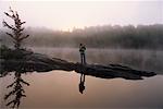 Woman Standing on Rocks near Lake With Fog at Sunset Haliburton, Ontario, Canada