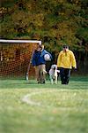 Zwei jungen Wandern durch Feld mit Fußball und Hund im Herbst