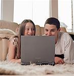 Teenage Boy et fille couché sur le plancher à l'aide d'ordinateur portable