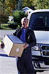 Portrait of Mature Male Courier Standing near Van, Holding Package, Ontario, Canada