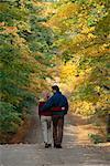 Vue arrière du Couple marchant sur le chemin à travers les arbres en automne Caledon, Ontario, Canada
