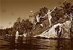 Couple en maillot de bain, sauter dans l'eau de lacs Belgrade Rocks, Maine, États-Unis
