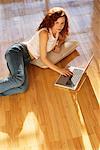 Portrait de femme allongée sur le sol avec ordinateur portable