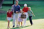 Family Walking through Field with Picnic Basket and Blanket