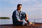 Portrait of Man Sitting on Dock With Laptop Computer