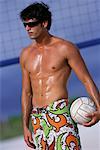 Mann am Strand, mit Sonnenbrille, halten Volleyball