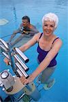 Mature Couple in Swimwear Exercising in Swimming Pool