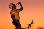 Man on Mountain Bike, Drinking Water at Sunset