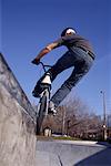 Back View of BMX Biker Grinding Wall with Pegs at Skatepark Toronto, Ontario, Canada