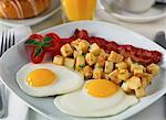 Close-Up of Breakfast Setting With Bacon, Eggs, Home Fries Juice, Coffee and Roll