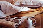 Femme sur lit d'hôtel en peignoir avec les Pages financières et Service à thé