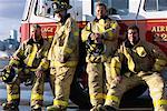 Portrait de groupe des pompiers se penchant sur le camion de pompier