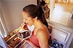 Femme se tenant près de réfrigérateur manger un gâteau au chocolat