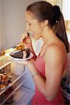 Woman Standing near Fridge Eating Chocolate Cake