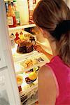 Vue arrière du femme prenant un gâteau au chocolat du frigo