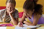 Two Girls Drawing in Notebooks In Bedroom