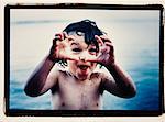 Portrait of Child Standing in Water, Making Face and Hand Gesture