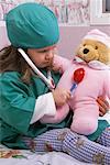 Girl Sitting on Bed in Doctor Costume, Playing Doctor with Teddy Bear