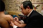 Male Artist Drawing Tattoo on Man's Arm Hong Kong