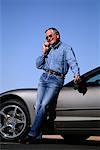 Mature Man Leaning on Sports Car Using Cell Phone