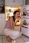 Portrait de femme accroupie fridge, manger la tarte aux fraise