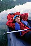 Mature Man Sleeping in Canoe on Water