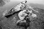 Back View of Mature Couple Relaxing on Shore with Canoe