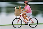 Mature Woman Riding Bike with Bags of Groceries