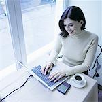 Woman Sitting by Window in Cafe Using Laptop Computer, Smiling