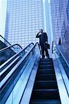 Businessman Standing at Top of Escalator, Using Cell Phone Los Angeles, California, USA