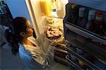 Femme debout au réfrigérateur, ayant Midnight Snack de tarte